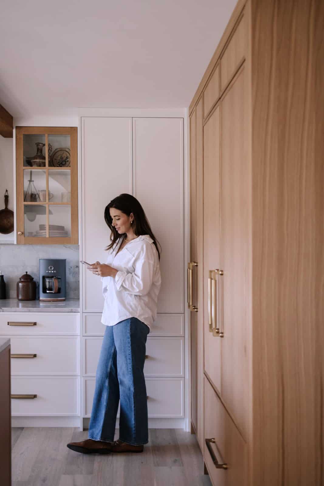 a woman standing in a kitchen looking at a phone - vegans oup brands